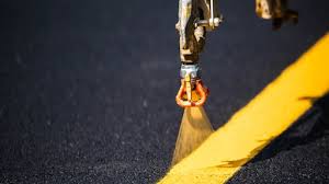yellow striping being applied to asphalt