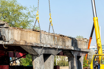 concrete bridge strapped to a crane for removal