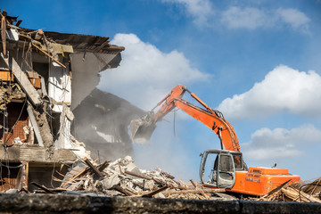 building being demolished by orange excavator