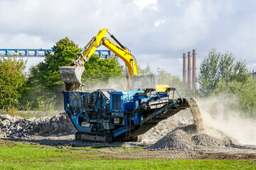 excavator dumping concrete in crushing machine